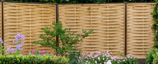 Woven fence using DuraPost® steel fence post in sepia brown with a colorful flower bed below 