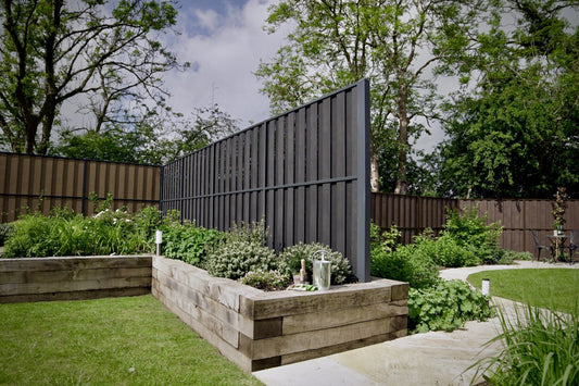 Image of a garden highlighting Durapost VENTO composite fence panels in both charcoal and sepia brown 